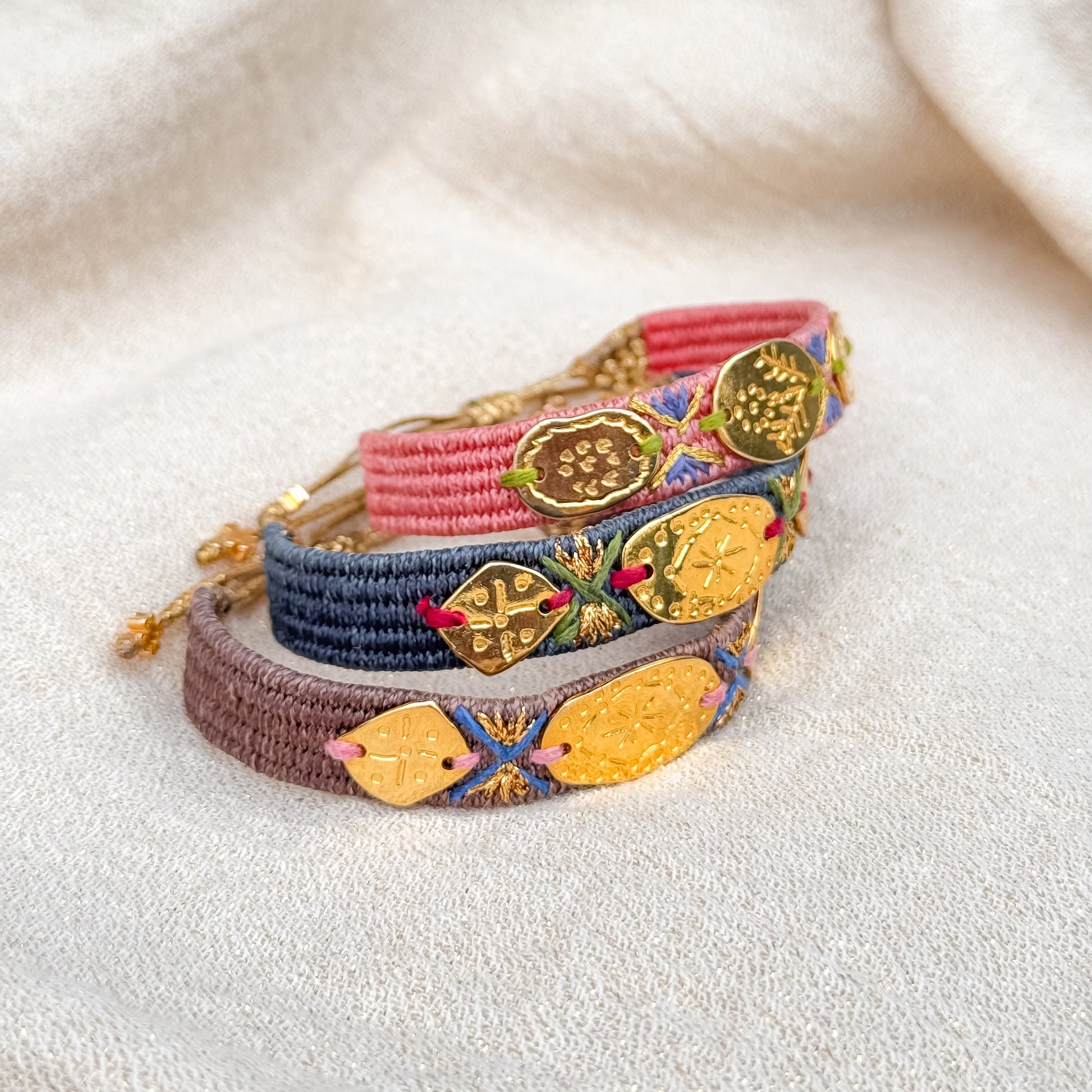 Colorful woven bracelets with decorative elements on a light fabric background