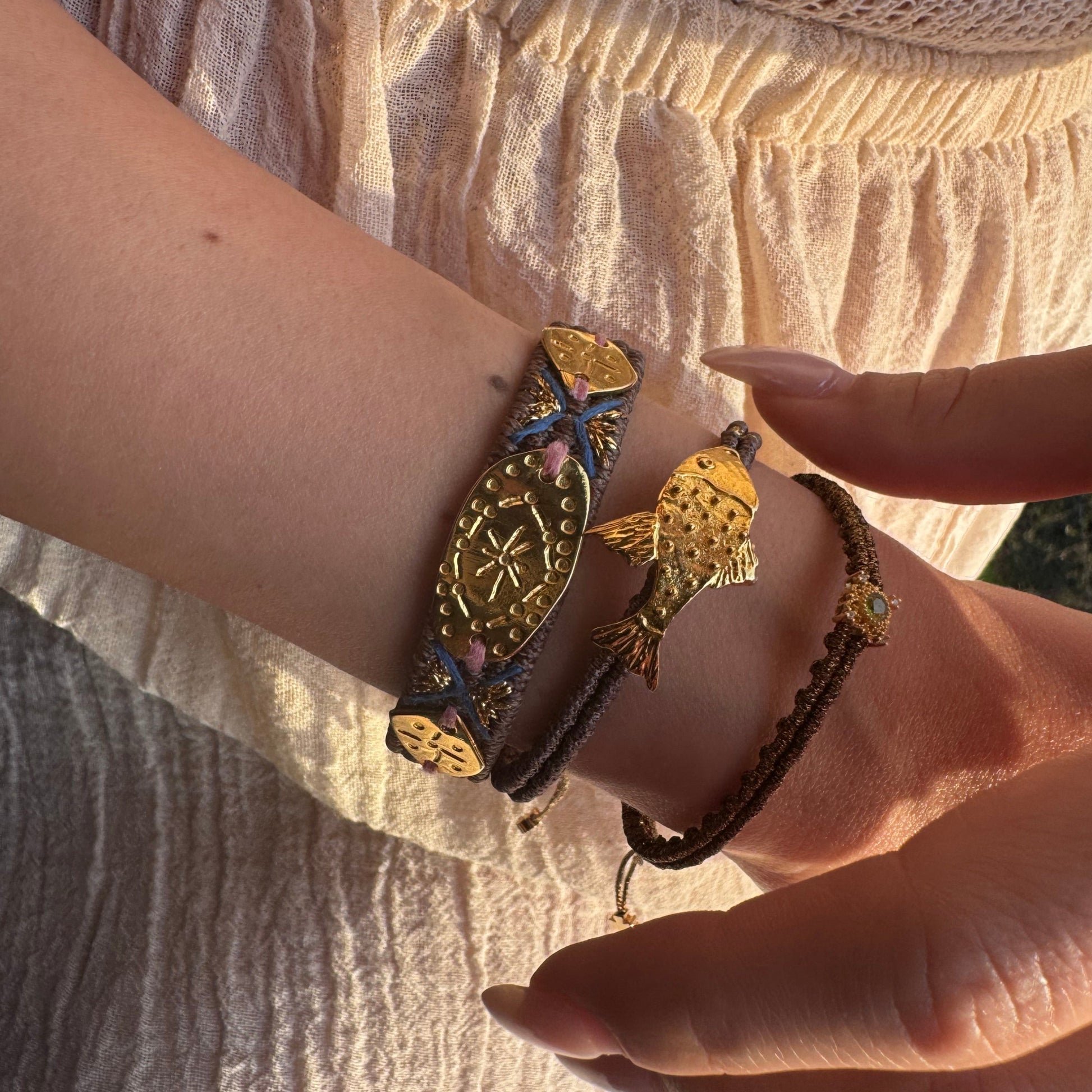 Close-up of a wrist wearing multiple bracelets on a textured fabric background