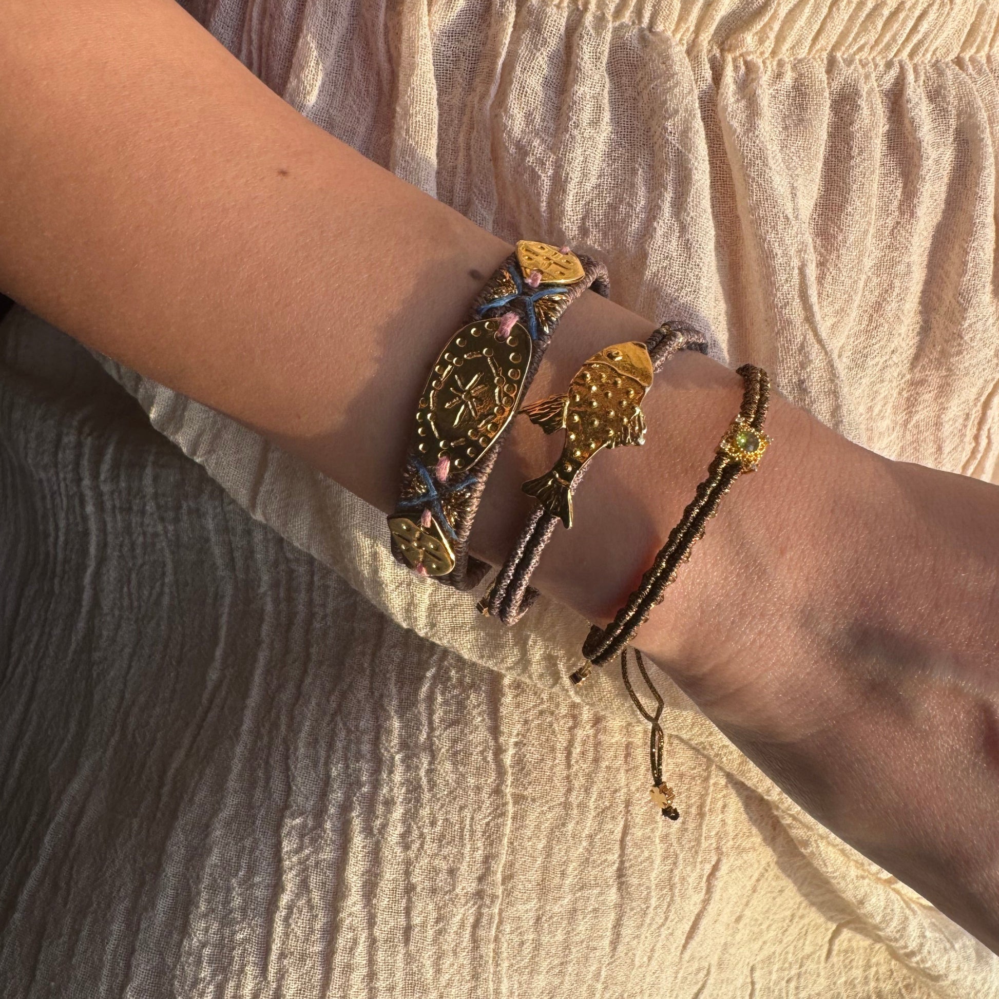 Close-up of a wrist wearing multiple bracelets on a textured beige background