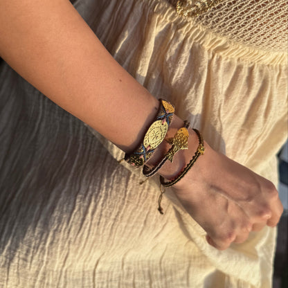 Close-up of a person's arm wearing multiple bracelets on a light fabric background