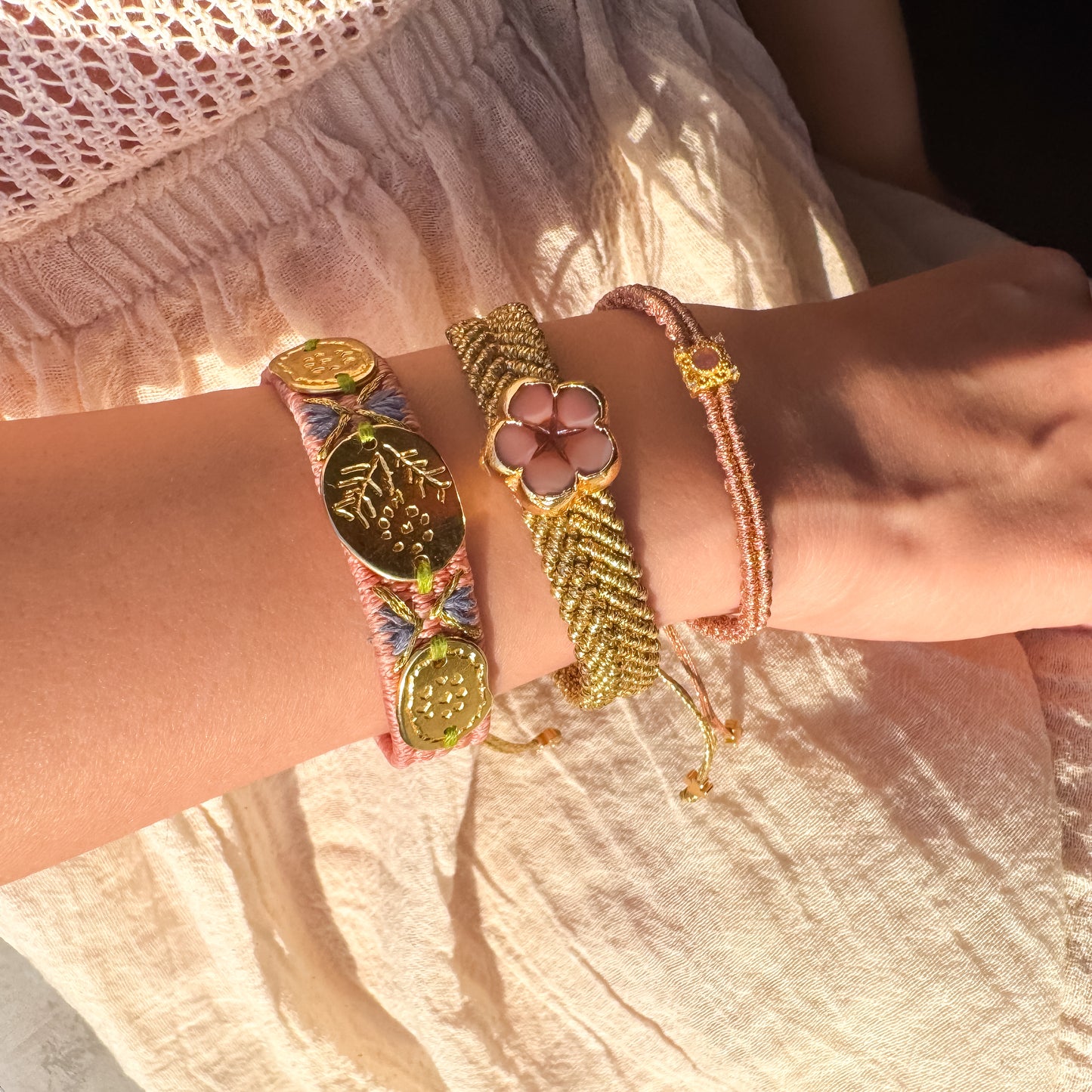 Close-up of a wrist wearing multiple colorful bracelets on a light fabric background