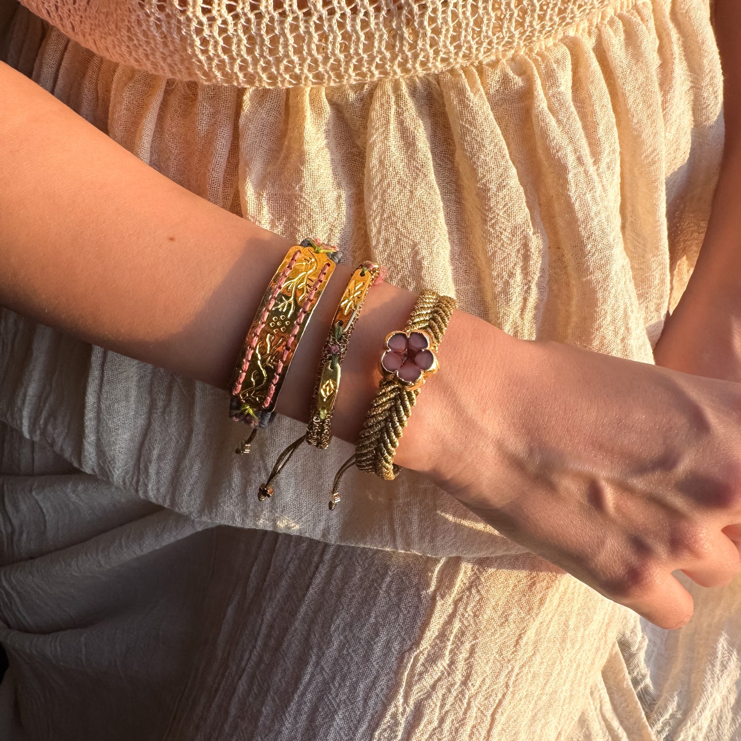 Close-up of a wrist wearing multiple bracelets with a neutral background