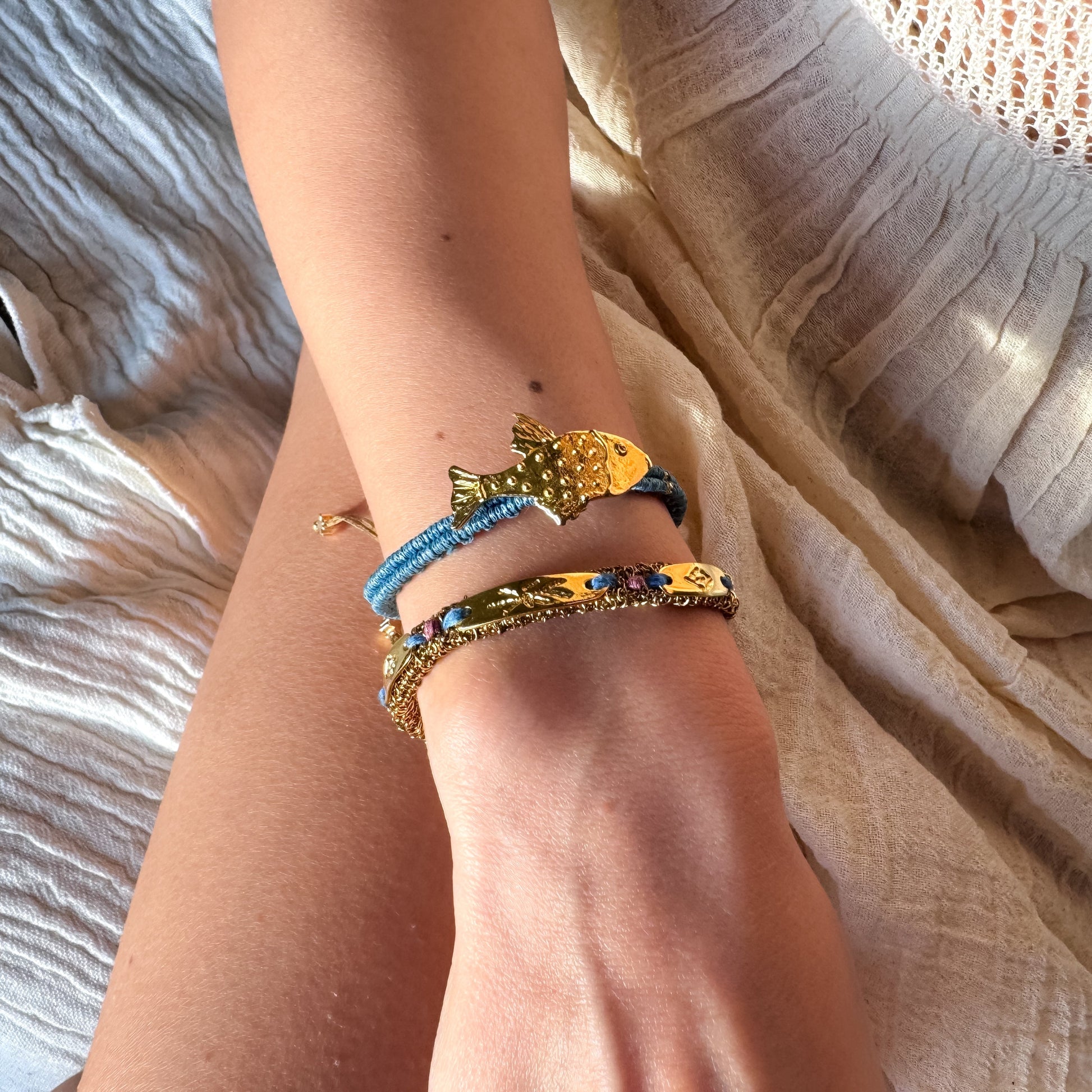 Close-up of a wrist wearing multiple colorful bracelets on a textured fabric background
